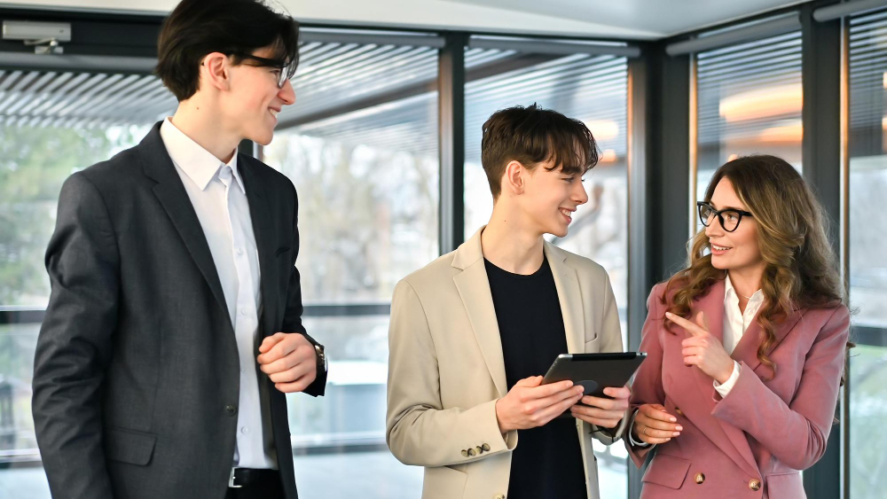 Three colleagues in smart attire share a light moment while walking with a tablet.